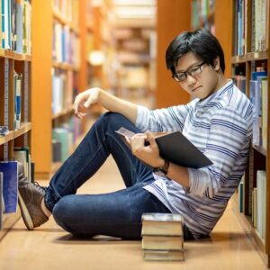 Smart Asian man student reading book in library