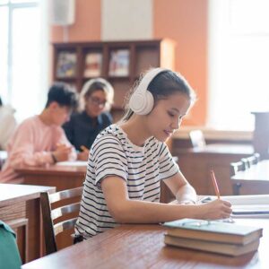Contemporary college student with headphones writing down plan o